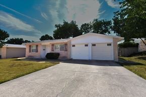 Dallas apartment for rent - A house with a white garage door is in front of a tree.