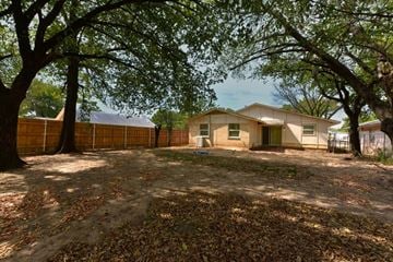 Dallas apartment for rent - A house is surrounded by trees and a fence.