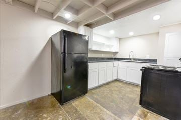 Dallas apartment for rent - A black refrigerator stands in a kitchen with white walls and a tiled floor.