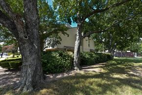 Dallas condo for rent - A house is surrounded by trees and greenery.