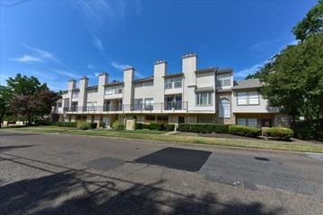 Dallas condo for rent - A large apartment building with a parking lot in front.