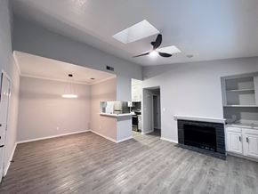 Dallas apartment for rent - A spacious living room with a fireplace and a kitchen area in the background.