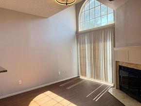 Dallas apartment for rent - A sunlit room with a fireplace and a large window with vertical blinds.