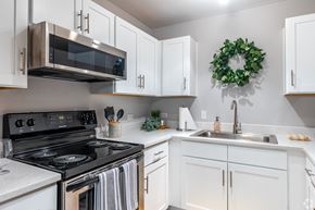 Dallas apartment for rent - A kitchen with a stove, microwave, and a wreath on the wall.
