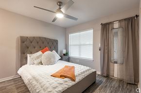 Dallas apartment for rent - A bedroom with a large bed and a ceiling fan.