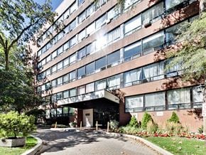 Toronto apartment for rent - A large red brick building with a glass entrance and a tree in front.