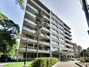 Toronto apartment for rent - A tall white apartment building with balconies and a green lawn in front.