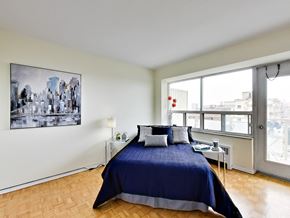 Toronto apartment for rent - A bedroom with a large bed and a cityscape picture on the wall.