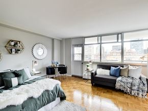 Toronto apartment for rent - A bedroom with a large bed and a couch with a view of the city.