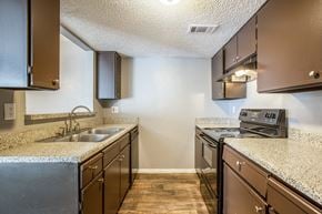 Dallas apartment for rent - A kitchen with brown cabinets and a granite countertop.
