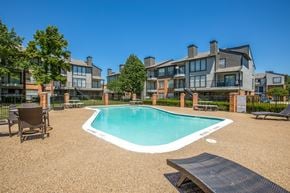 Dallas apartment for rent - A swimming pool surrounded by a fence and chairs.