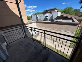 Kingston apartment for rent - A balcony with a black railing and a view of a house and trees.