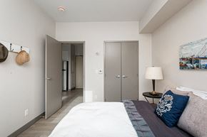 Kingston apartment for rent - A bedroom with a bed, a lamp, and a painting on the wall.