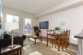 Kingston apartment for rent - A living room with a black couch, a wooden dining table, and a television.