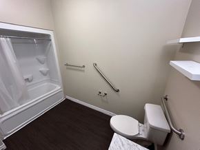Kingston apartment for rent - A small bathroom with a toilet, a shower with a glass door, and a grab bar.