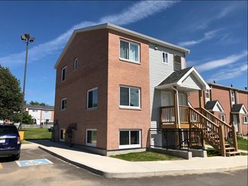 Kingston apartment for rent - A two-story brick apartment building with a blue car parked in front.