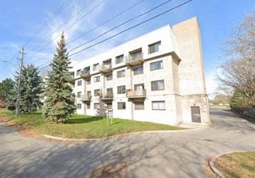 Kingston apartment for rent - A white apartment building with a green lawn in front.