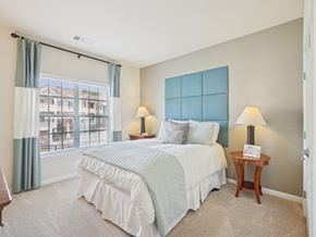 Raleigh apartment for rent - A bedroom with a large bed and a window with a view of a building outside.