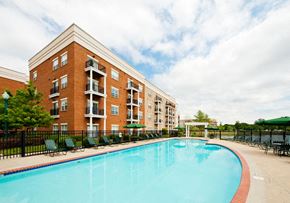 Newport News apartment for rent - Pool with chairs and umbrellas next to apartment building and pond