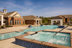 Richmond apartment for rent - Dog-Friendly Apartments in Richmond, VA - Clairmont at Chesterfield - Resort-Style Swimming Pool With Bubbling Hot Tub, Wide Sundeck, Clubhouse Building, and Covered Pavilion Under Blue Sky.