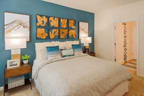 Charlotte apartment for rent - Pet-Friendly Luxury Apartments in Charlotte, North Carolina - Belmont at Tryon - Bedroom With Blue Accent Wall, Decorative Pillows, Matching Nightstands With Lamps, And Framed Wall Art.