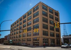 Buffalo apartment for rent - A large brown building with many windows is in the middle of a street.