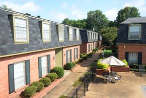 Jackson apartment for rent - A sunny day at a brick apartment complex with a patio and a table.
