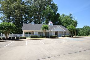 Vicksburg apartment for rent - A building with a flag on top and a parking lot in front.