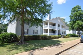 Vicksburg apartment for rent - A white two-story house with a tree in front.
