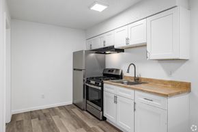 Oklahoma City apartment for rent - A kitchen with white cabinets and a wooden countertop.
