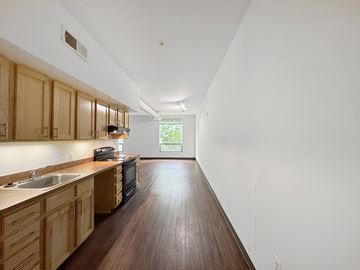 Washington apartment for rent - A long, narrow kitchen with wooden cabinets and a dark countertop.