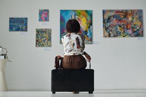 Silver Spring apartment for rent - A woman is sitting on a suitcase looking at paintings on the wall.