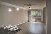 Dallas townhouse for rent - Open-concept living and dining area with wood-look flooring, ceiling fan, and sliding glass door in a one-bedroom apartment home
