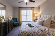 Dallas townhouse for rent - A bedroom with a bed, nightstand, and a ceiling fan in the 826 square foot 1 bedroom, 1 bathroom apartment at The Brownstones Townhome Apartments in the Far North Dallas neighborhood of Dallas, TX.