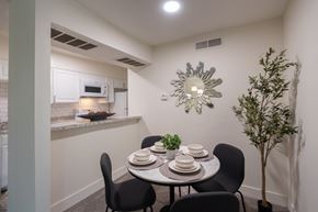 Dallas apartment for rent - A dining area with a table set for four and a potted plant with a view of the kitchen pass-through window in a 1 bedroom, 1 bath 554 sq ft apartment home at The Biltmore Apartments located in the Vickery Midtown neighborhood of Dallas, TX.