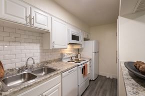 Dallas apartment for rent - A kitchen with white appliances and white cabinets in a 1 bedroom, 1 bath 554 sq ft apartment home at The Biltmore Apartments located in the Vickery Midtown neighborhood of Dallas, TX.