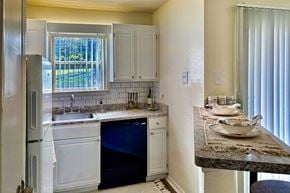 Dallas apartment for rent - Kitchen in an Efficiency apartment at Cambridge Court Apartments in Dallas, Texas, featuring white cabinetry, range, sink, counter space, and a window.