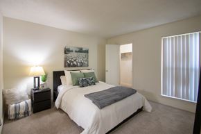 Dallas apartment for rent - A bedroom with a large bed and a painting on the wall in a 515 square foot 1 bedroom, 1 bath apartment home at Canyon Creek Apartments in Dallas Midtown neighborhood of Dallas, TX.