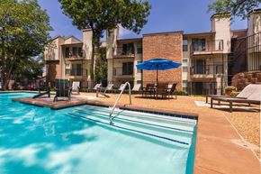 Dallas apartment for rent - A swimming pool in front of apartment buildings at Canyon Creek Apartments in the Dallas Midtown neighborhood of Dallas, TX.