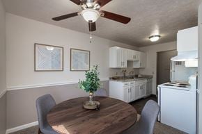 Fairfield apartment for rent - Dining area in the Fairfield Pointe 1-bedroom apartment, with a round table, ceiling fan, framed wall art, and kitchen in the background.