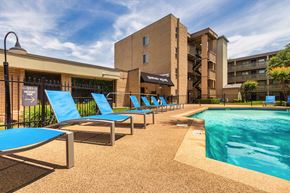 Dallas apartment for rent - Pool deck with blue lounge chairs and apartment buildings at Harvard Square Apartments in Dallas