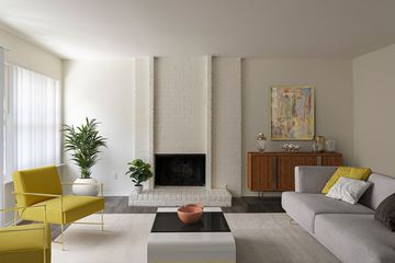 Dallas apartment for rent - a living room with a gray couch and yellow chairs and a fireplace