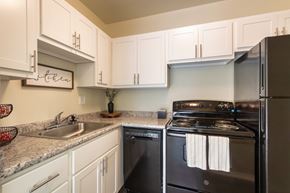 Cincinnati apartment for rent - A kitchen with black appliances and white cabinets.