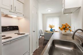 Dallas apartment for rent - A kitchen with a stove, sink, and a dining table with chairs.