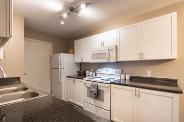 Centerville apartment for rent - A kitchen with white cabinets and black countertops.