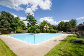 Philadelphia apartment for rent - A blue swimming pool surrounded by green grass and trees at Brookshire Trace Townhomes Apartments, Pennsylvania