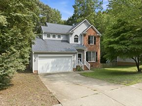 Wake Forest apartment for rent - A two-story house with a garage is surrounded by trees.