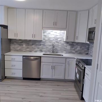 Raleigh townhouse for rent - A kitchen with white cabinets and a grey backsplash.