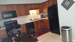 Raleigh townhouse for rent - A kitchen with a black refrigerator and wooden cabinets.