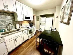 Raleigh triplex for rent - A kitchen with a black table and white cabinets.